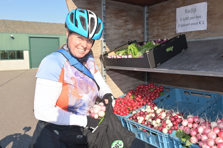 Fietsburgemeester Marja van der Ende doet per fiets boodschappen bij een groentestal.