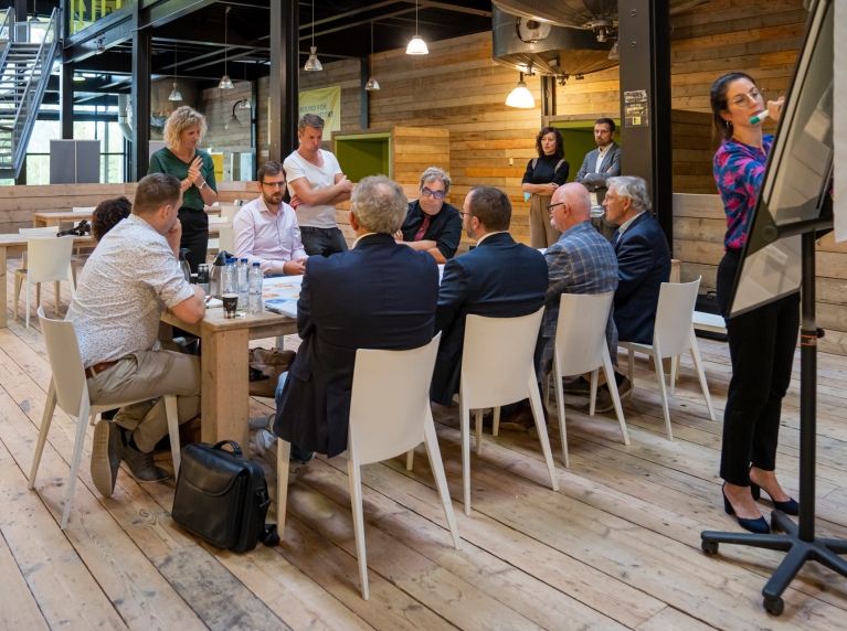 Mensen rondom een tafel zijn in gesprek over de Strategische Agenda MRDH. Iemand schrijft wat op het bord.