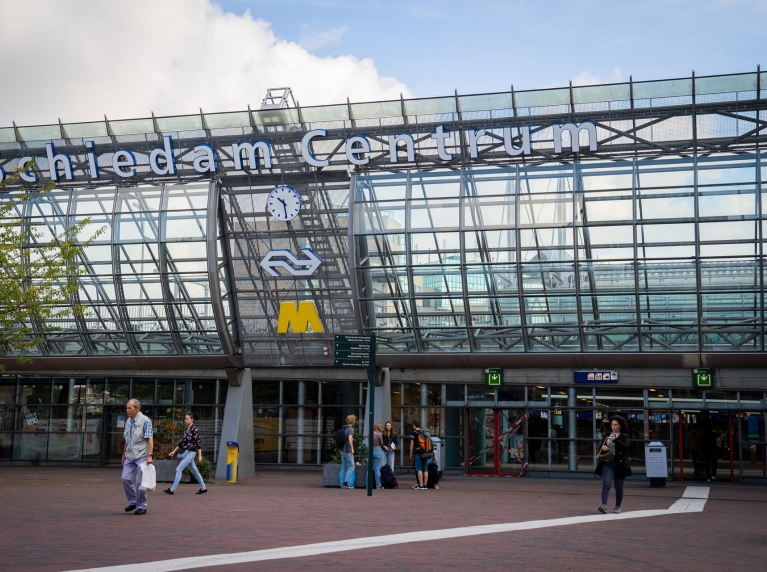 Voetgangers lopen bij de ingang van station Schiedam Centrum