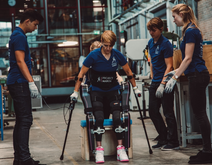 Studenten helpen een proefpersoon met het lopen met een exoskelet. Het is een innovatie toepassing in de zorgtechnologie